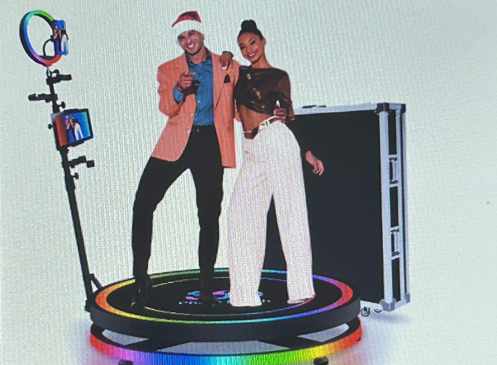 Couple posing on 360 photo booth platform with RGB lighting